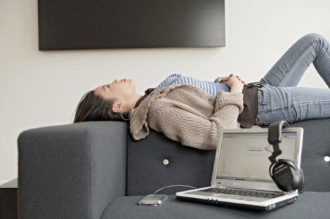Woman resting beside headphone and laptop, side view